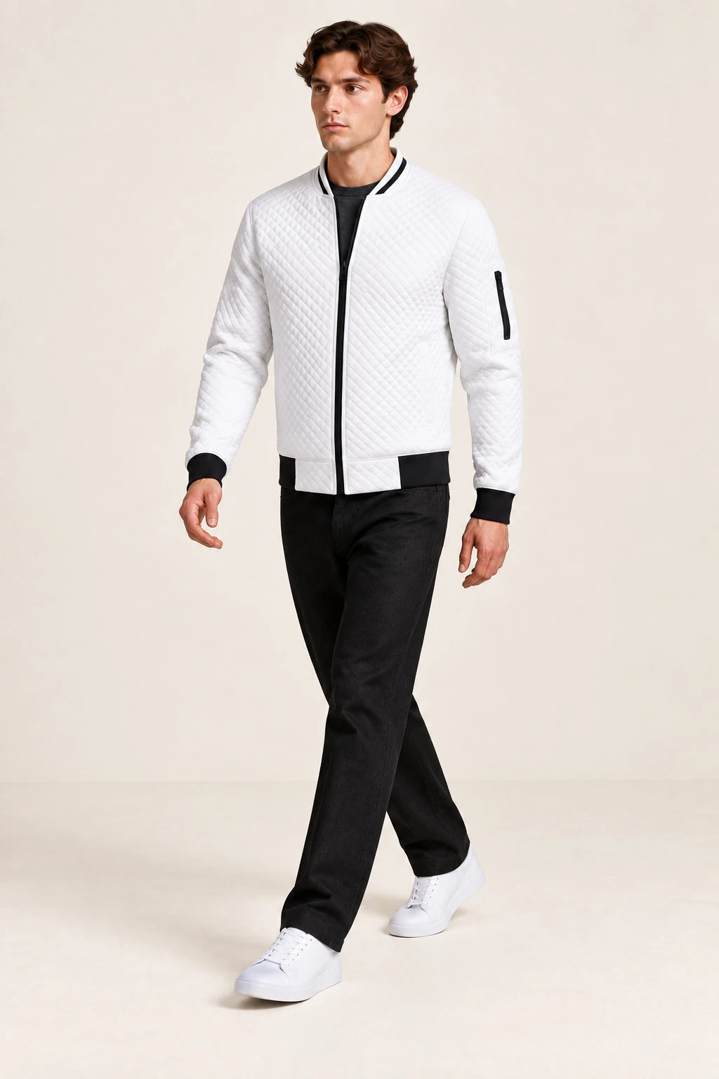 Veste bomber blanche matelassée en losanges, portée en marche de trois-quarts dans le studio IVAREE.
