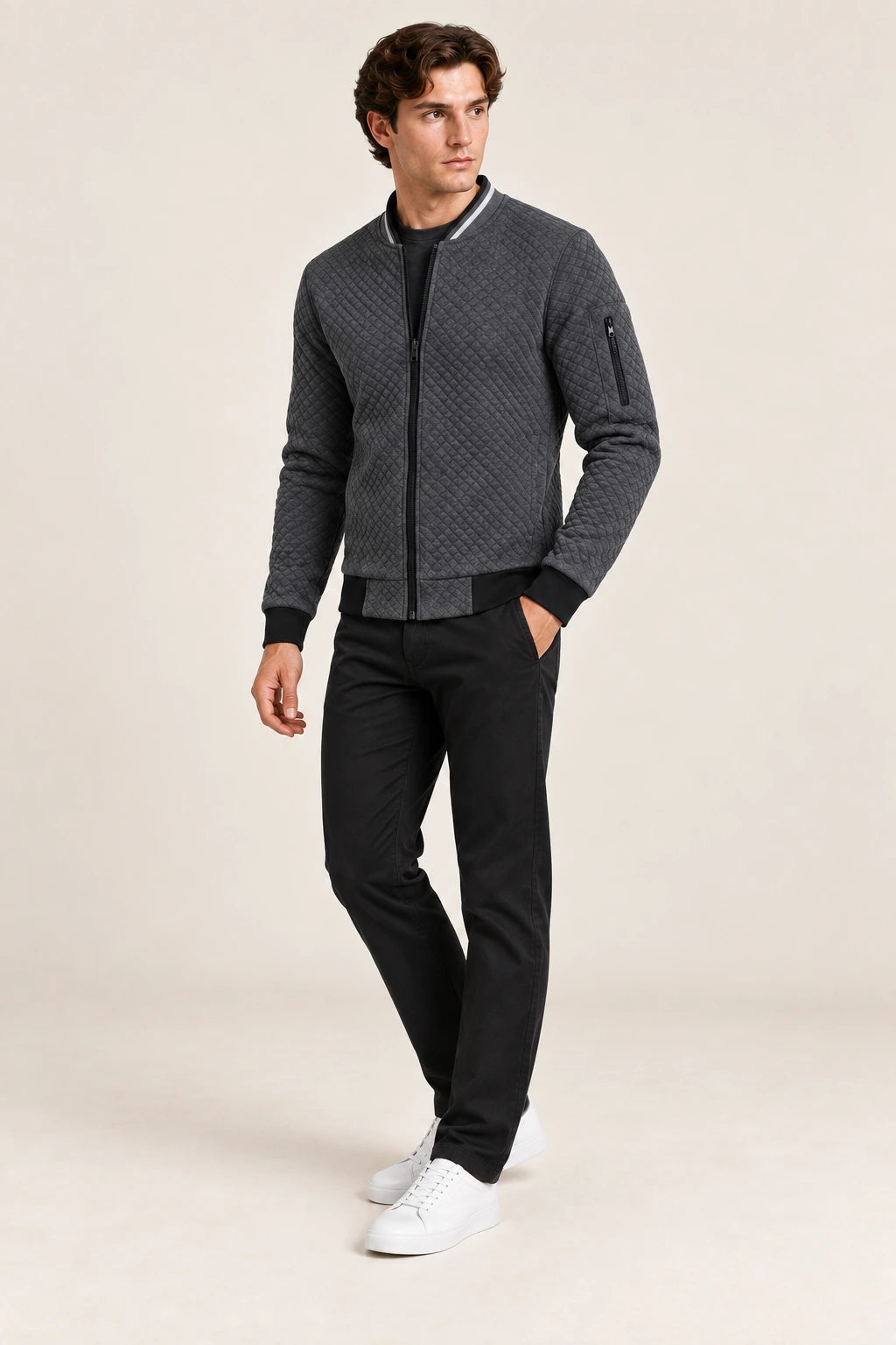 Veste bomber gris foncé matelassée en losanges, troisième pose dynamique dans le studio IVAREE.