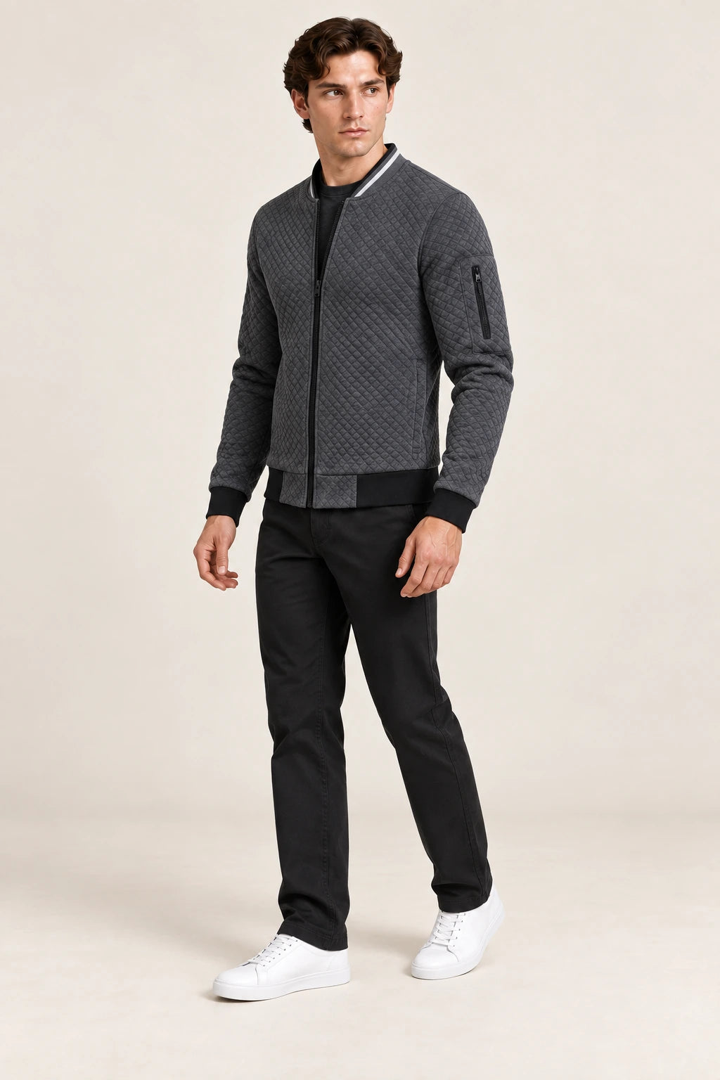Veste bomber gris foncé matelassée en losanges, portée de trois-quarts dans le studio IVAREE.