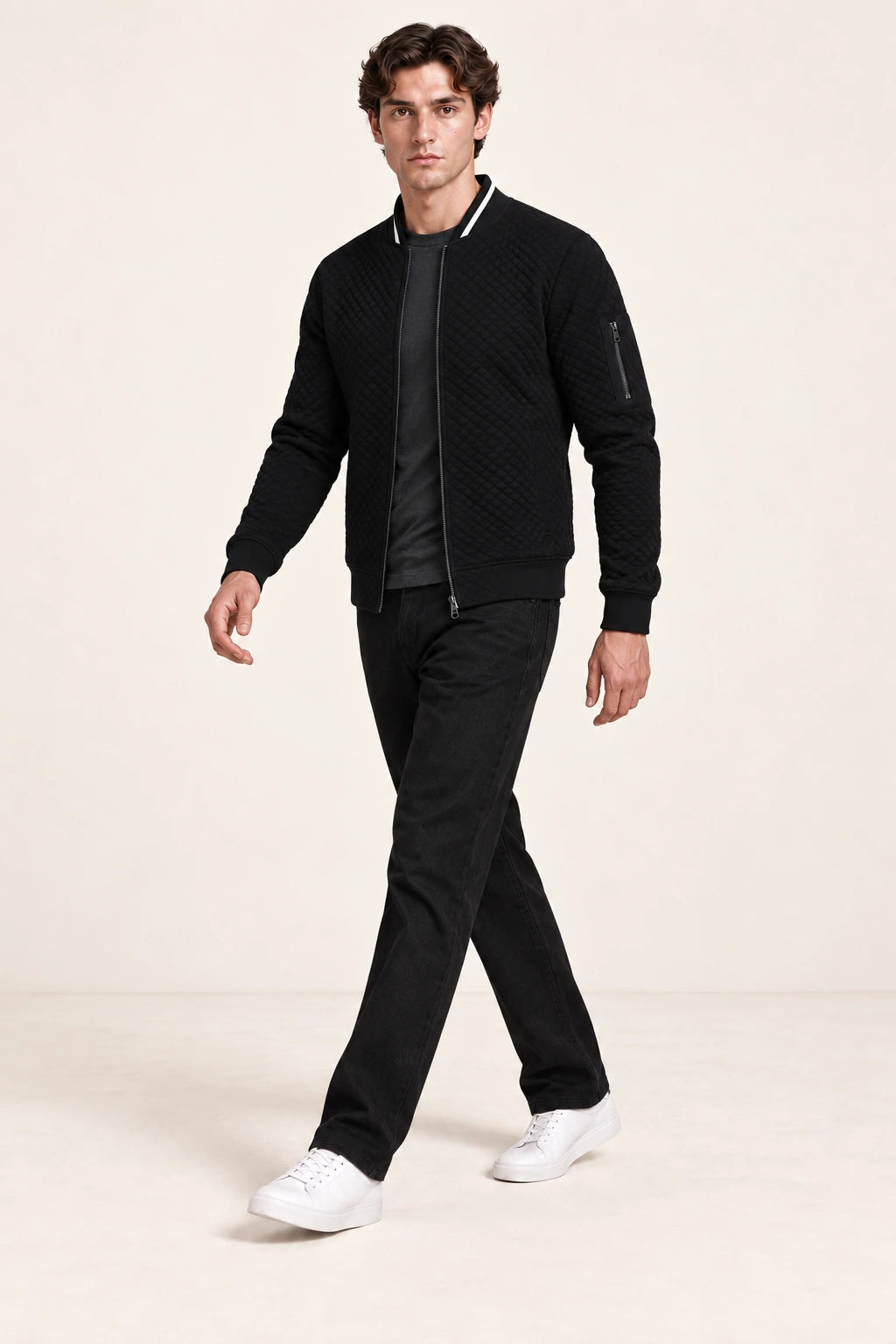 Veste bomber noire matelassée en losanges, troisième pose en marche dans le studio IVAREE.