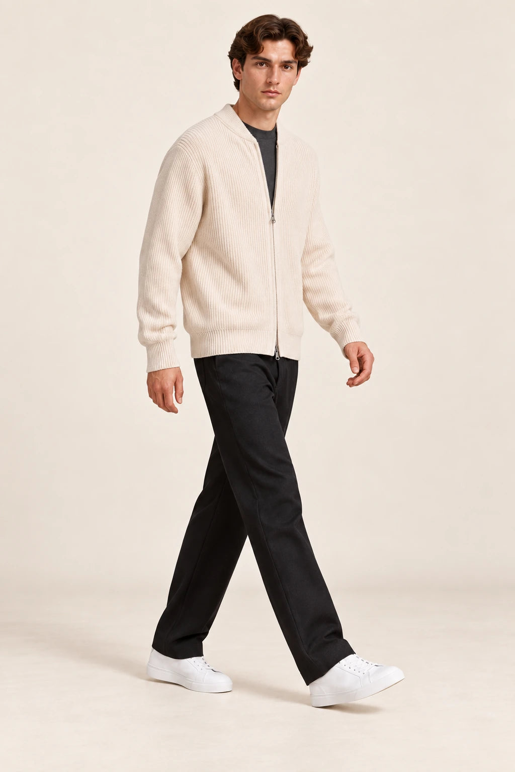 Cardigan beige en maille côtelée fine, troisième vue en marche de trois-quarts dans le studio IVAREE.