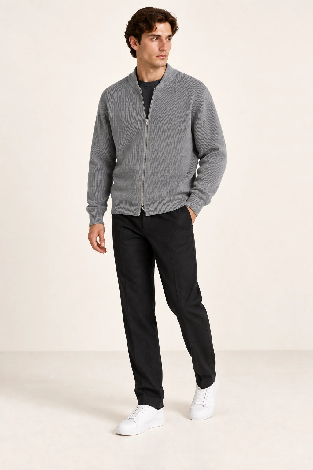 Cardigan gris en maille côtelée fine avec fermeture zippée, porté de trois-quarts dans le studio IVAREE.