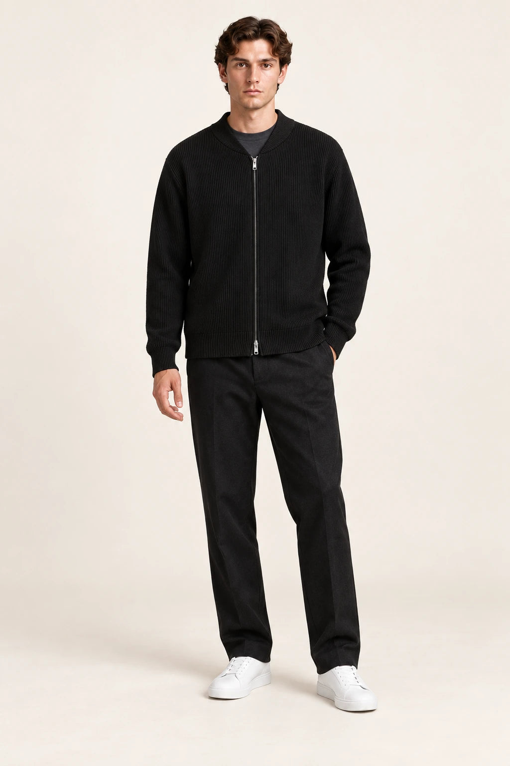 Cardigan noir en maille côtelée fine avec col court et fermeture zippée à double curseur, porté de face dans le studio IVAREE.