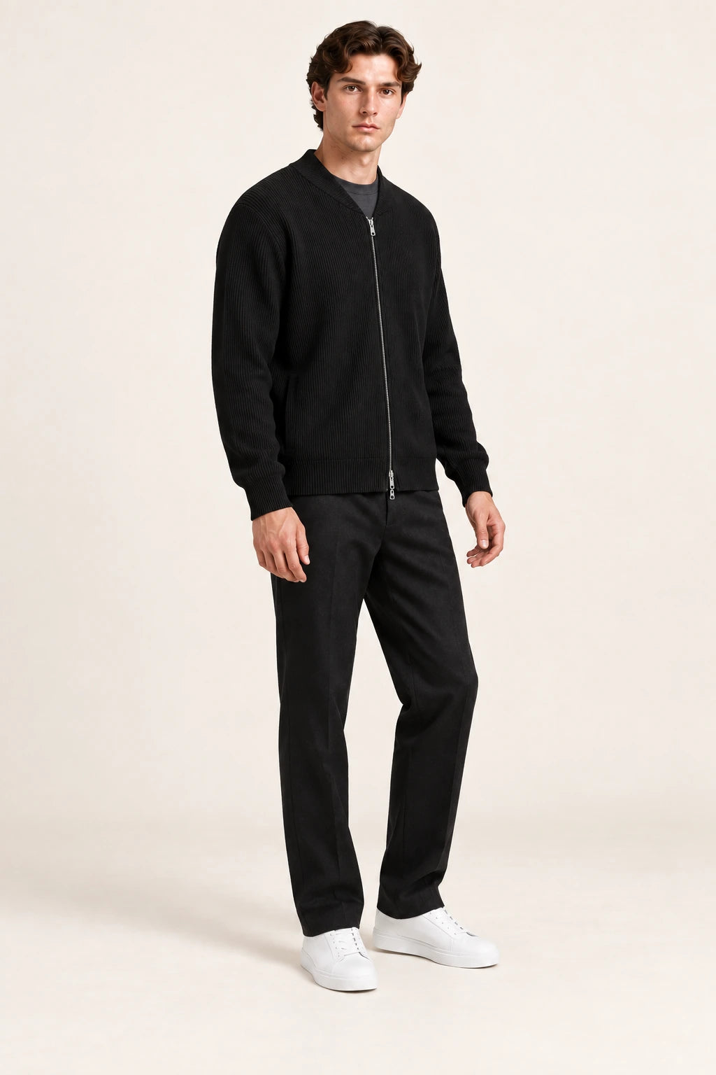 Cardigan noir en maille côtelée fine avec fermeture zippée, porté de trois-quarts dans le studio IVAREE.