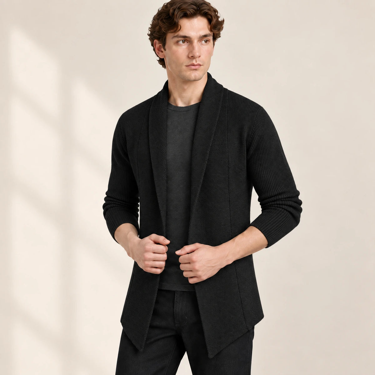 Cardigan long noir ouvert en maille côtelée, vu de trois-quarts avant dans le studio IVAREE.
