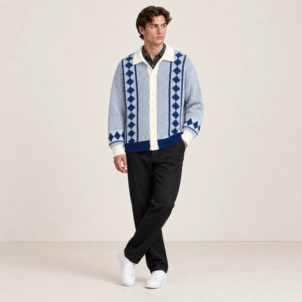 Cardigan bleu clair et écru en maille ajourée à losanges, porté dans une pose jambes croisées dans le studio IVAREE.