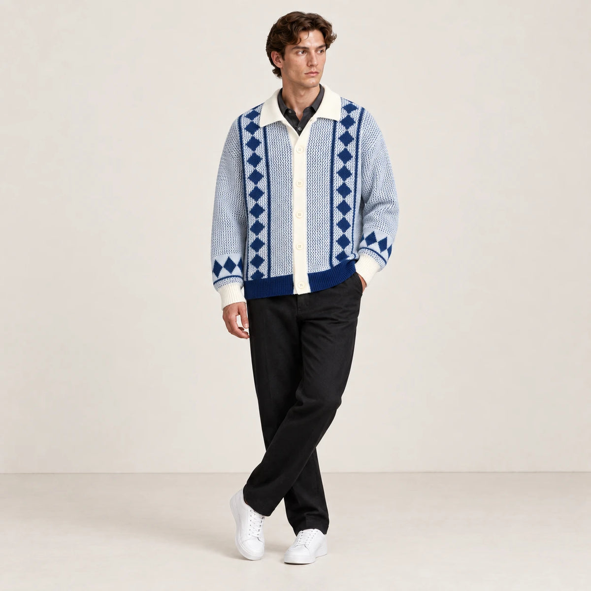 Cardigan bleu clair et écru en maille ajourée à losanges, porté dans une pose jambes croisées dans le studio IVAREE.