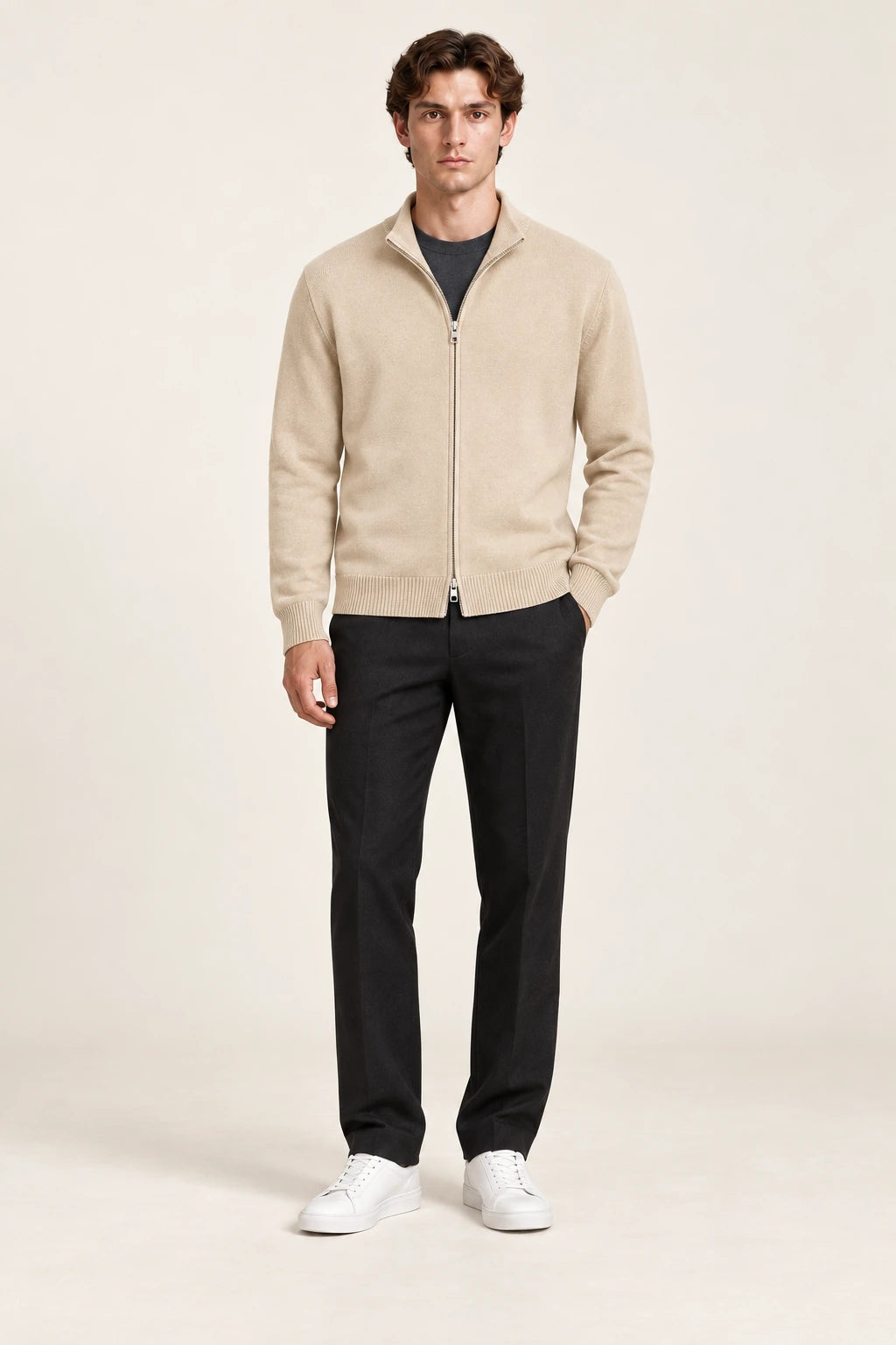 Cardigan beige en maille fine coupe slim avec col court et fermeture zippée à double curseur, porté de face dans le studio IVAREE.