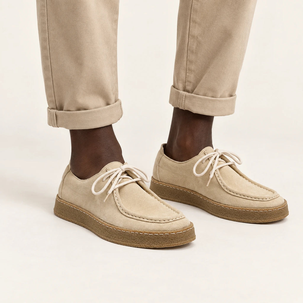 Chaussures moc-toe en daim à semelle crêpe beige, portées debout dans le studio IVAREE