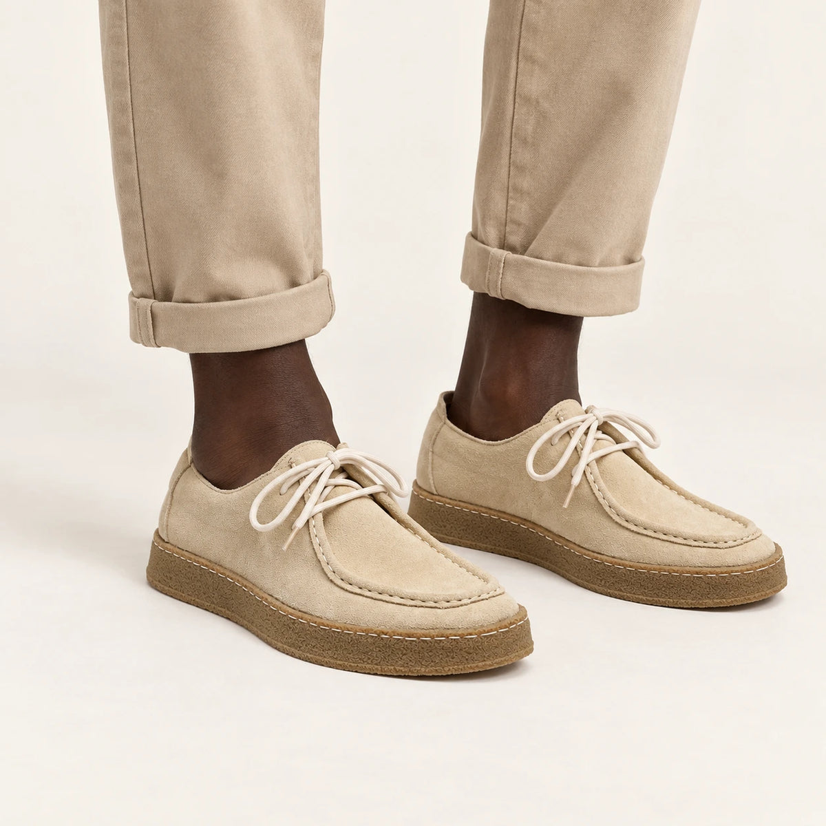 Chaussures moc-toe en daim à semelle crêpe beige, portées debout dans le studio IVAREE