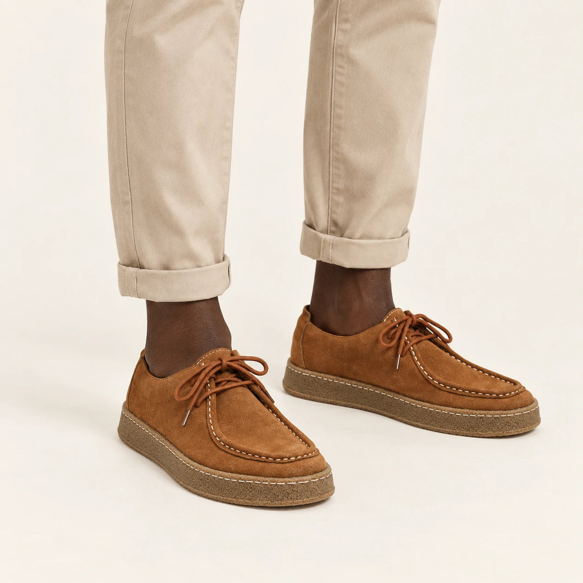 Chaussures moc-toe en daim à semelle crêpe caramel, portées debout dans le studio IVAREE