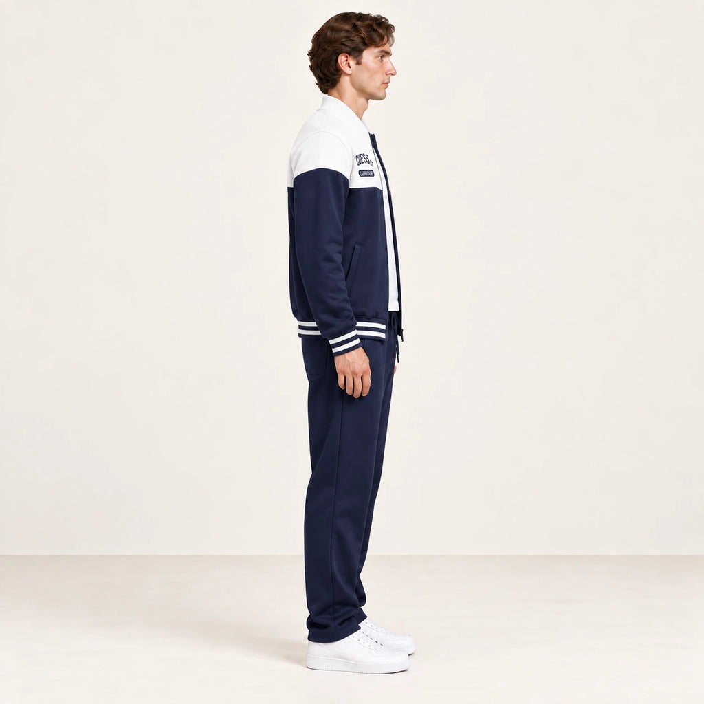 Ensemble de survêtement esprit baseball blanc et bleu marine, porté de profil en studio ivoire