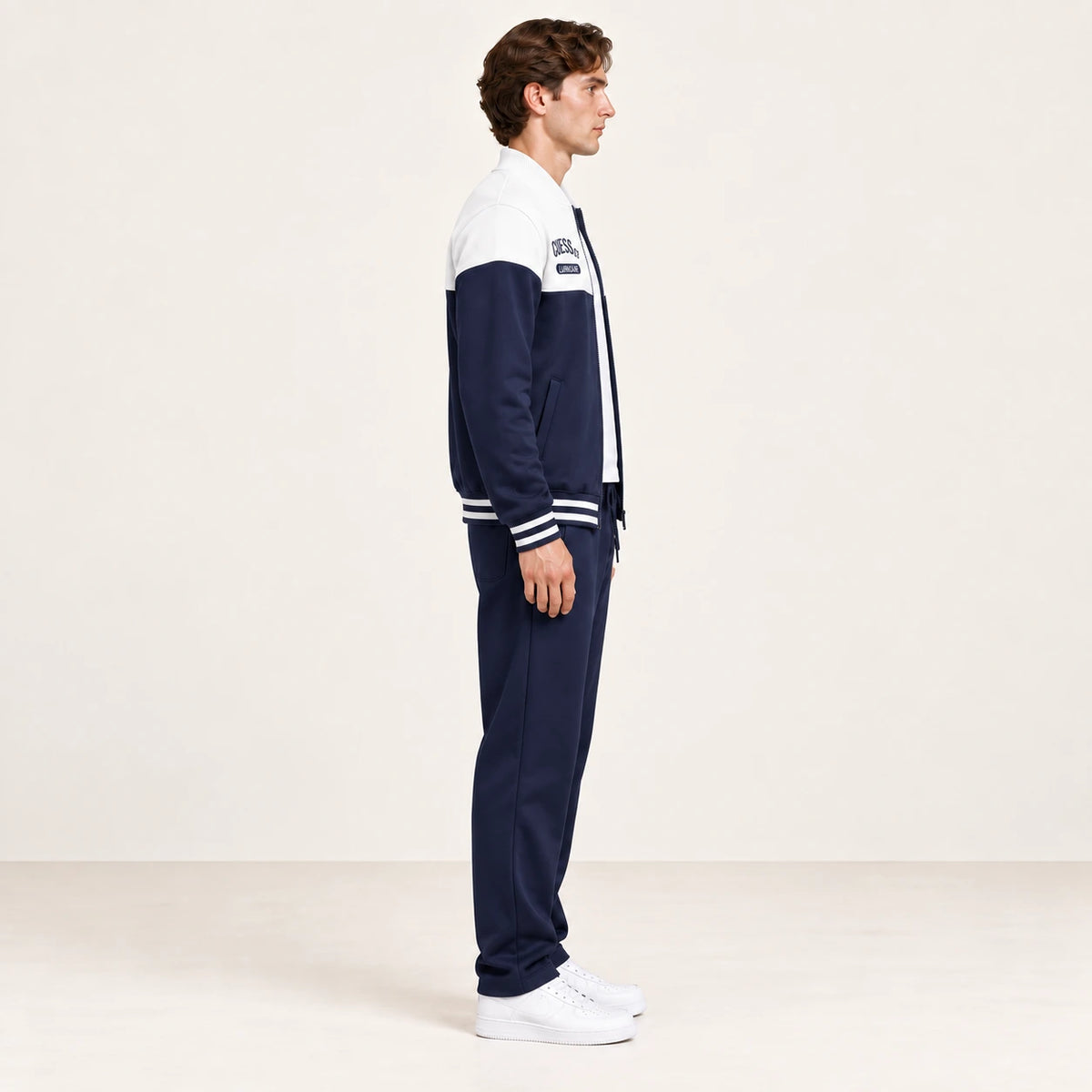 Ensemble de survêtement esprit baseball blanc et bleu marine, porté de profil en studio ivoire