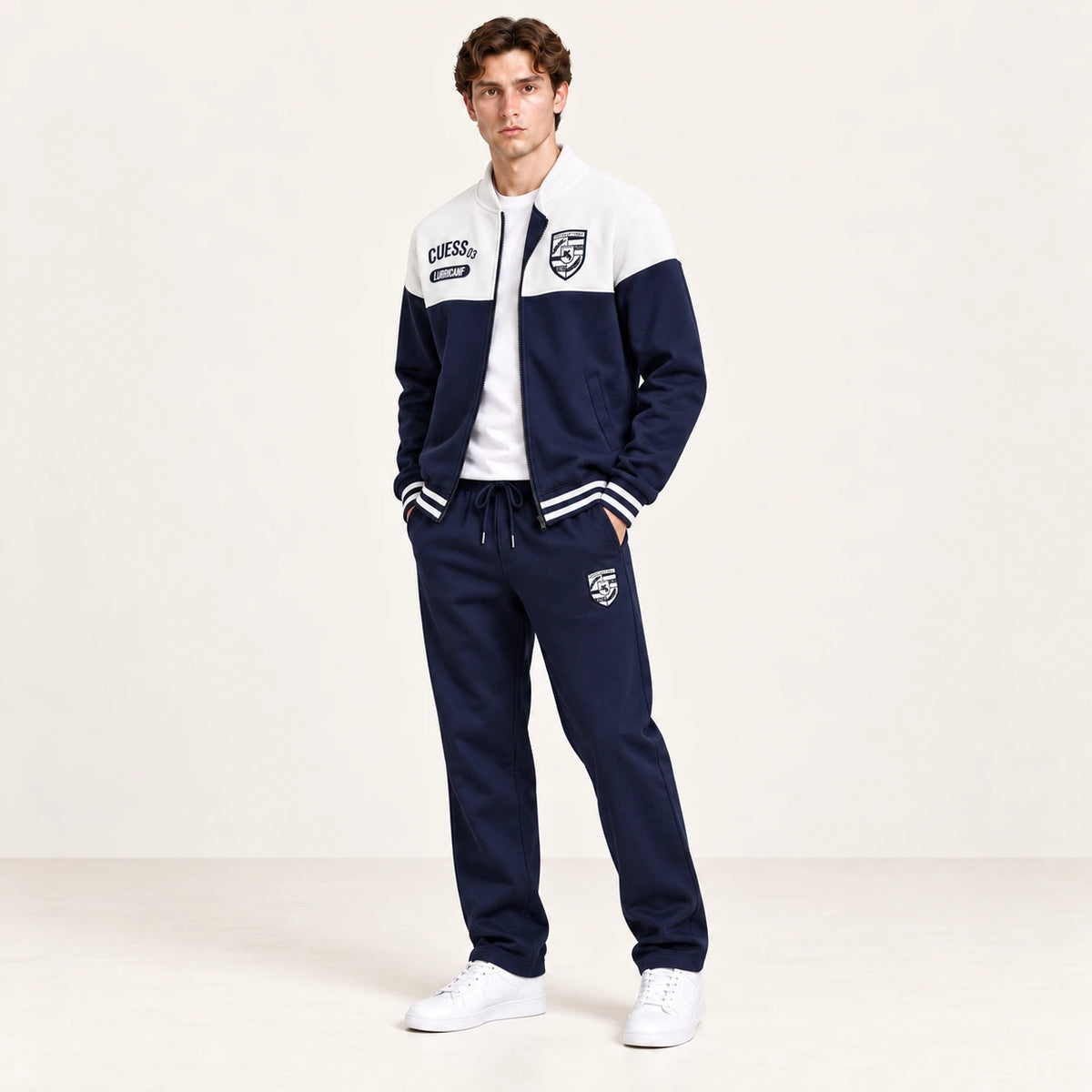Ensemble de survêtement esprit baseball blanc et bleu marine, porté en vue trois-quarts en studio ivoire