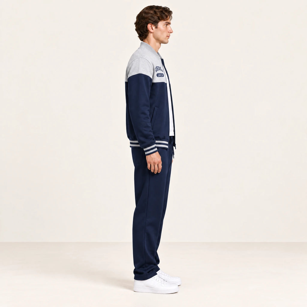 Ensemble de survêtement esprit baseball gris clair et bleu marine, porté de profil en studio ivoire