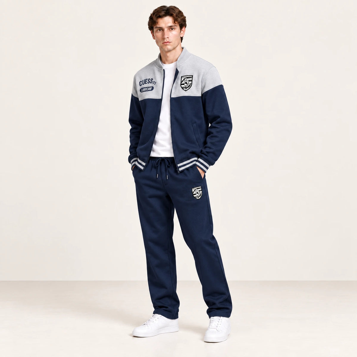 Ensemble de survêtement esprit baseball gris clair et bleu marine, porté en vue trois-quarts en studio ivoire