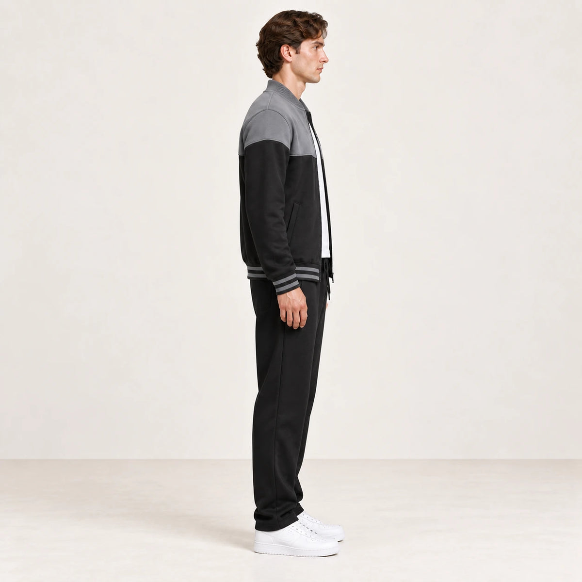 Ensemble de survêtement esprit baseball gris et noir, porté de profil en studio ivoire