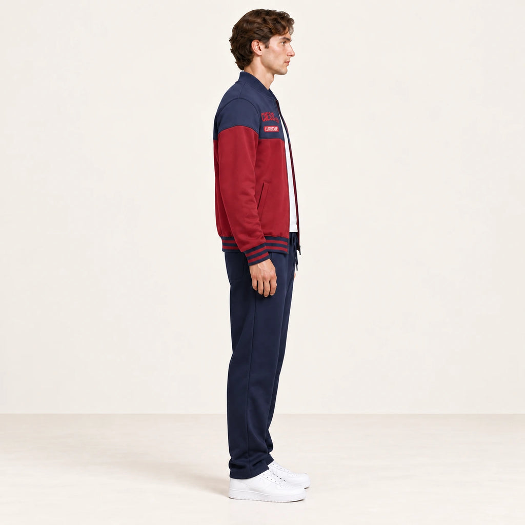 Ensemble de survêtement esprit baseball rouge et bleu marine, porté de profil en studio ivoire