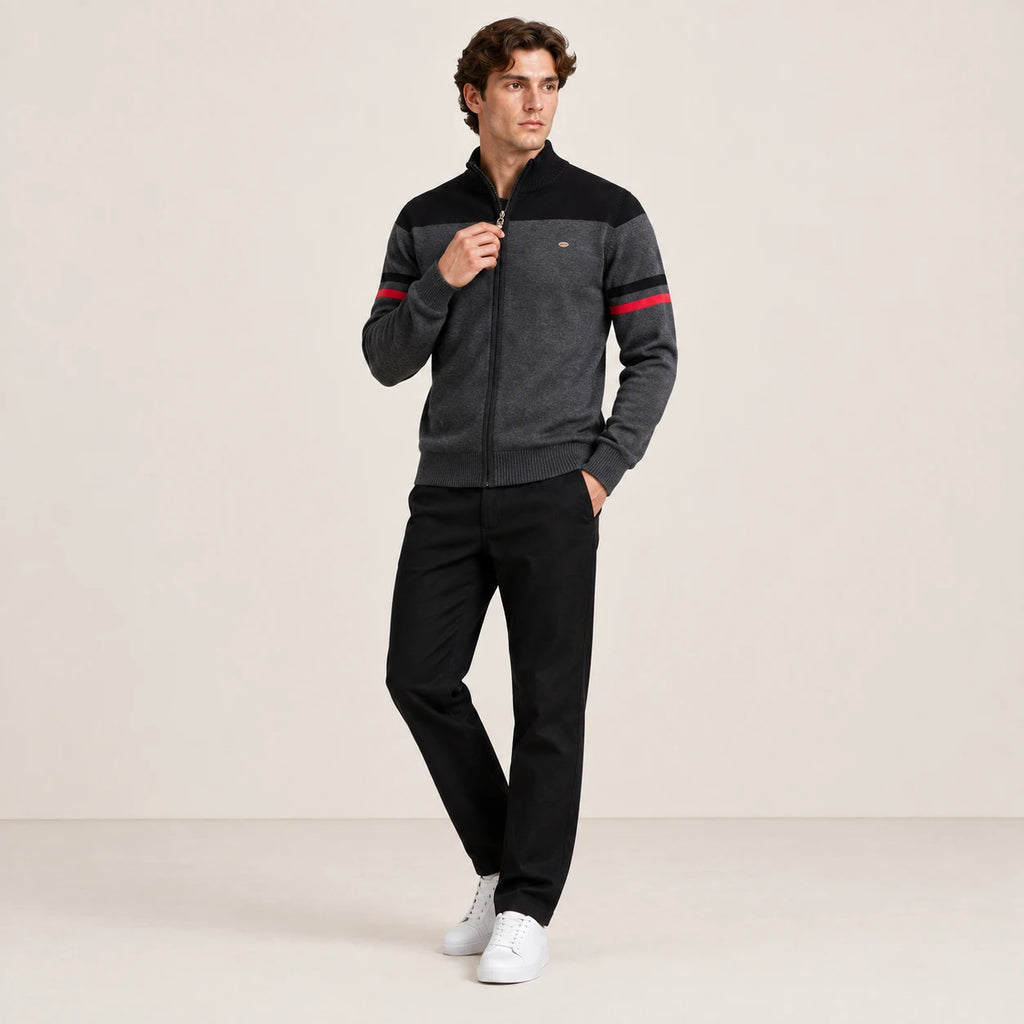 Gilet zippé gris anthracite et noir à col cheminée, porté avec une main sur le zip dans le studio IVAREE.