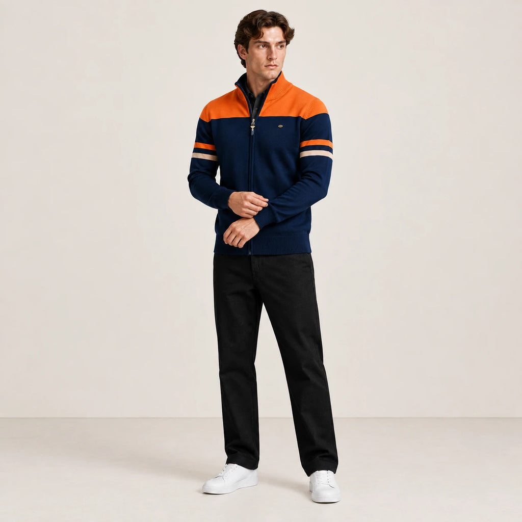 Gilet zippé bleu marine et orange à col cheminée, porté en ajustant le poignet dans le studio IVAREE.