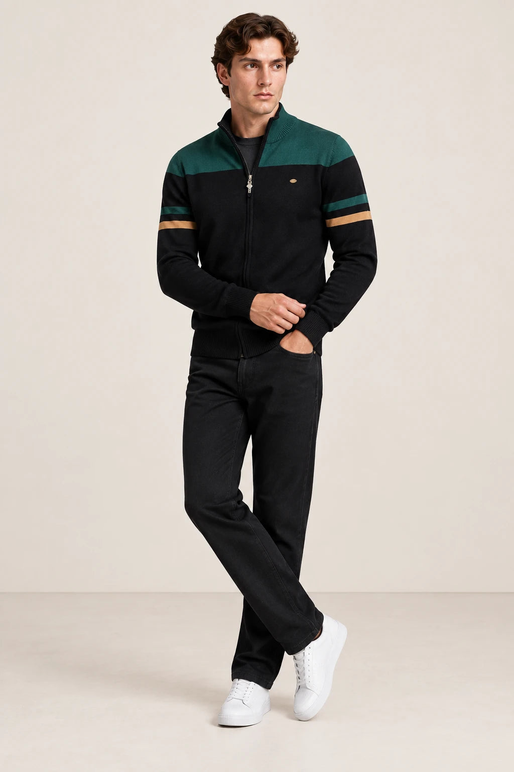 Gilet zippé noir et vert foncé à col cheminée, porté en ajustant le poignet dans le studio IVAREE.