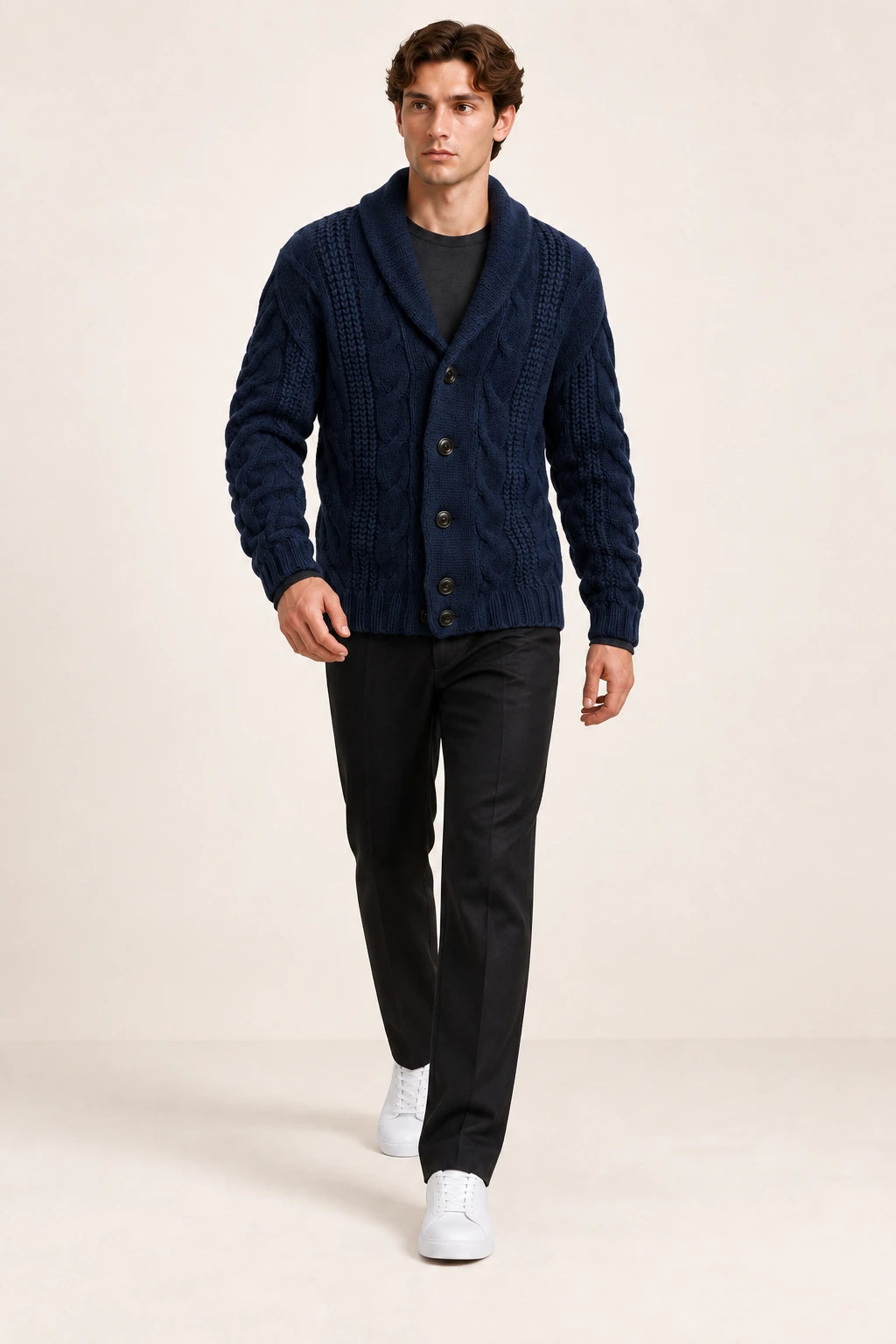 Cardigan bleu foncé en maille épaisse torsadée à col châle, porté en marche de trois-quarts dans le studio IVAREE.