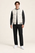 Gilet sans manches beige matelassé à col et base côtelés rayés, porté de face dans le studio IVAREE.