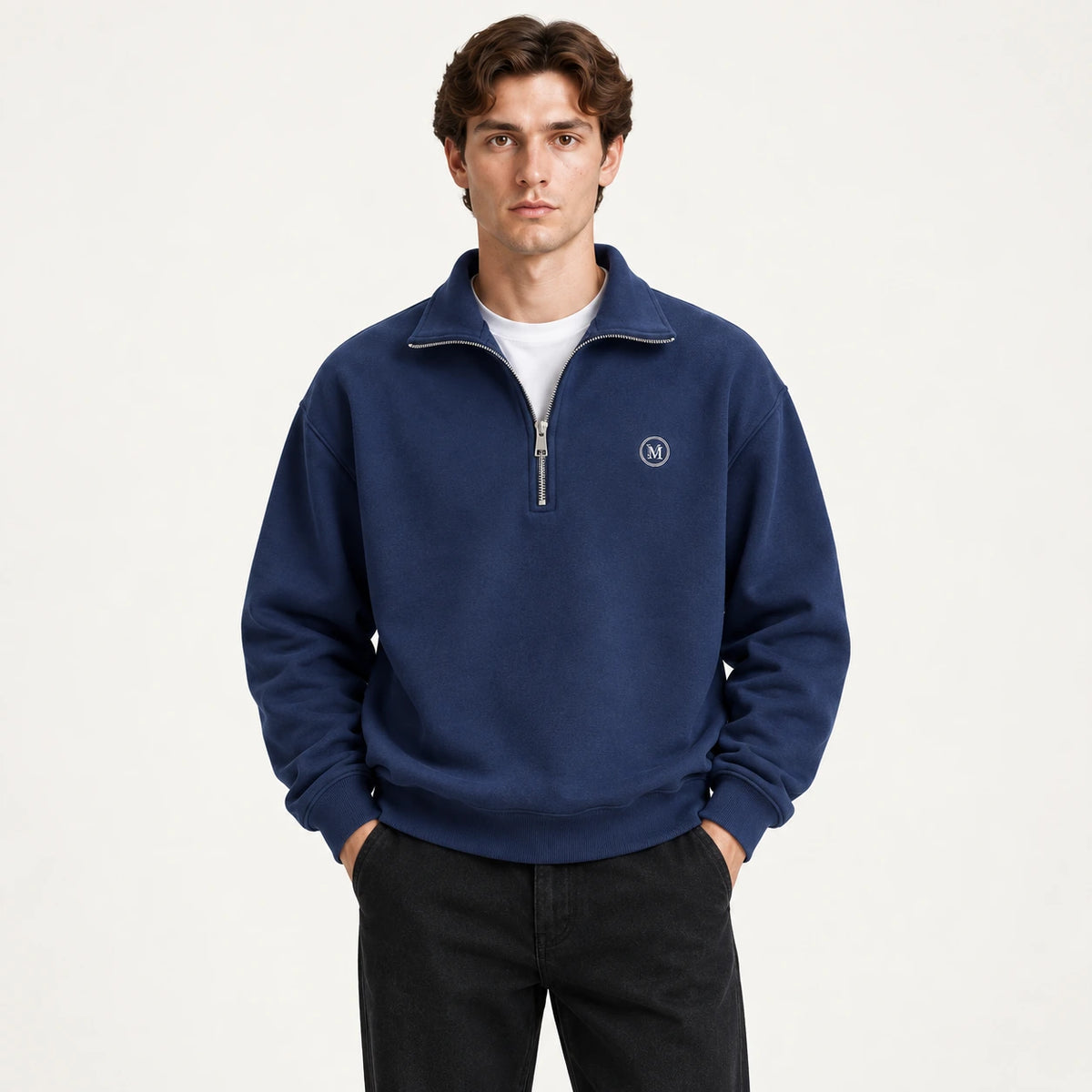 Détail du gilet bleu à zip quart, col montant et écusson circulaire, dans le studio IVAREE.