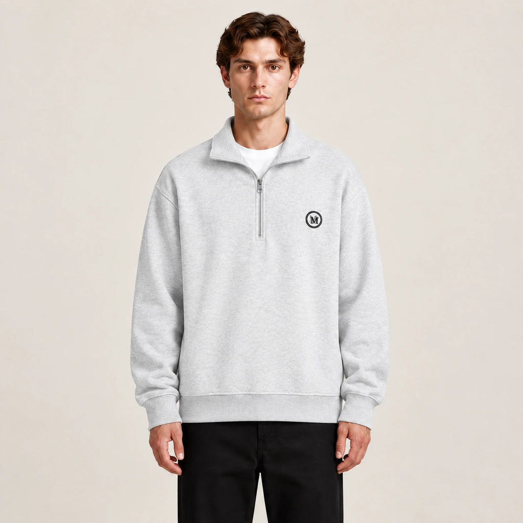 Détail du gilet gris à zip quart, col montant et écusson circulaire, dans le studio IVAREE.