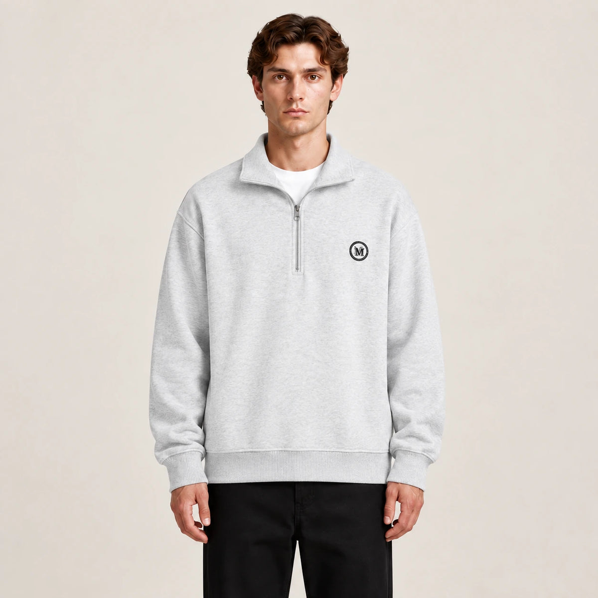 Détail du gilet gris à zip quart, col montant et écusson circulaire, dans le studio IVAREE.