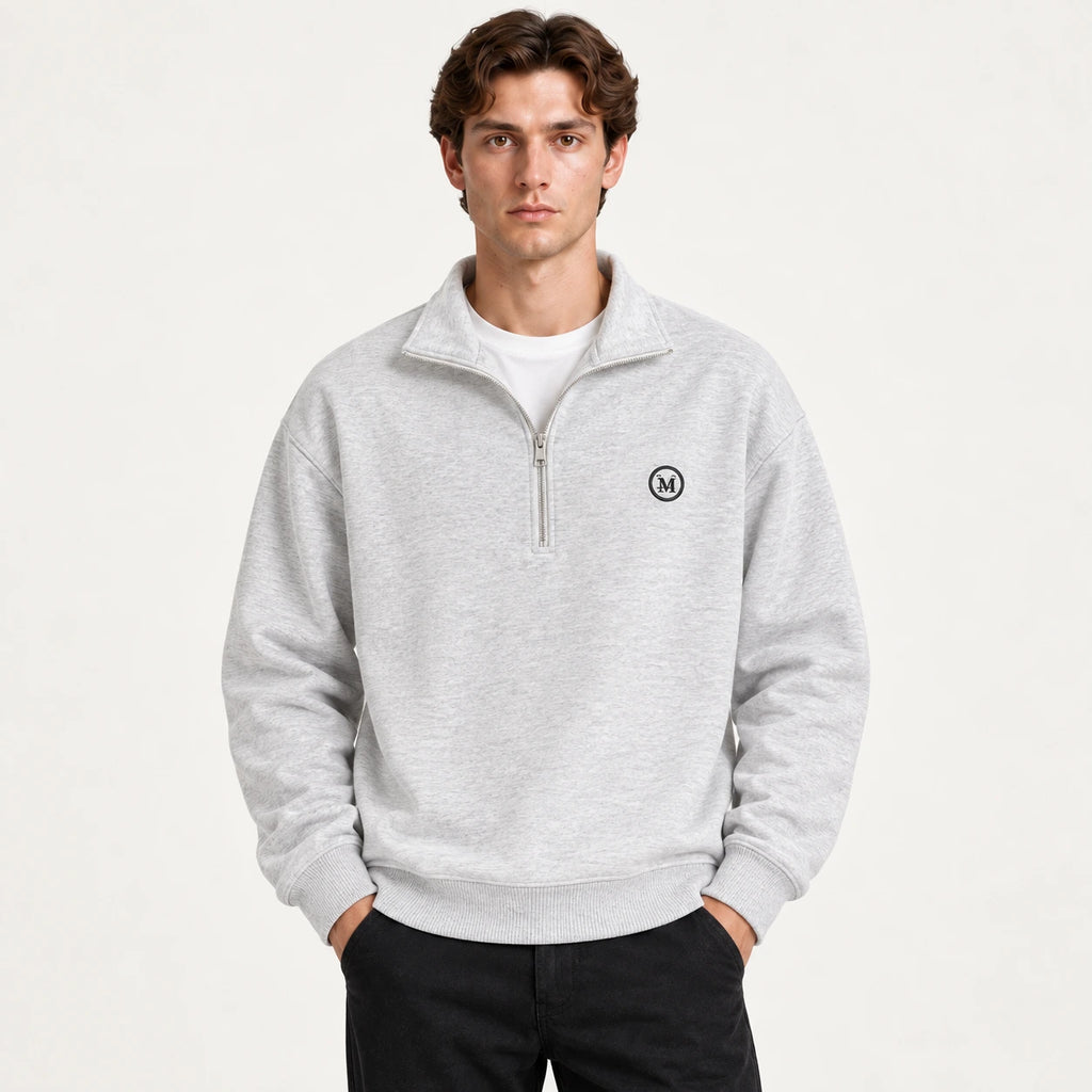Détail du gilet gris à zip quart, col montant, bords-côtes et écusson circulaire, dans le studio IVAREE.