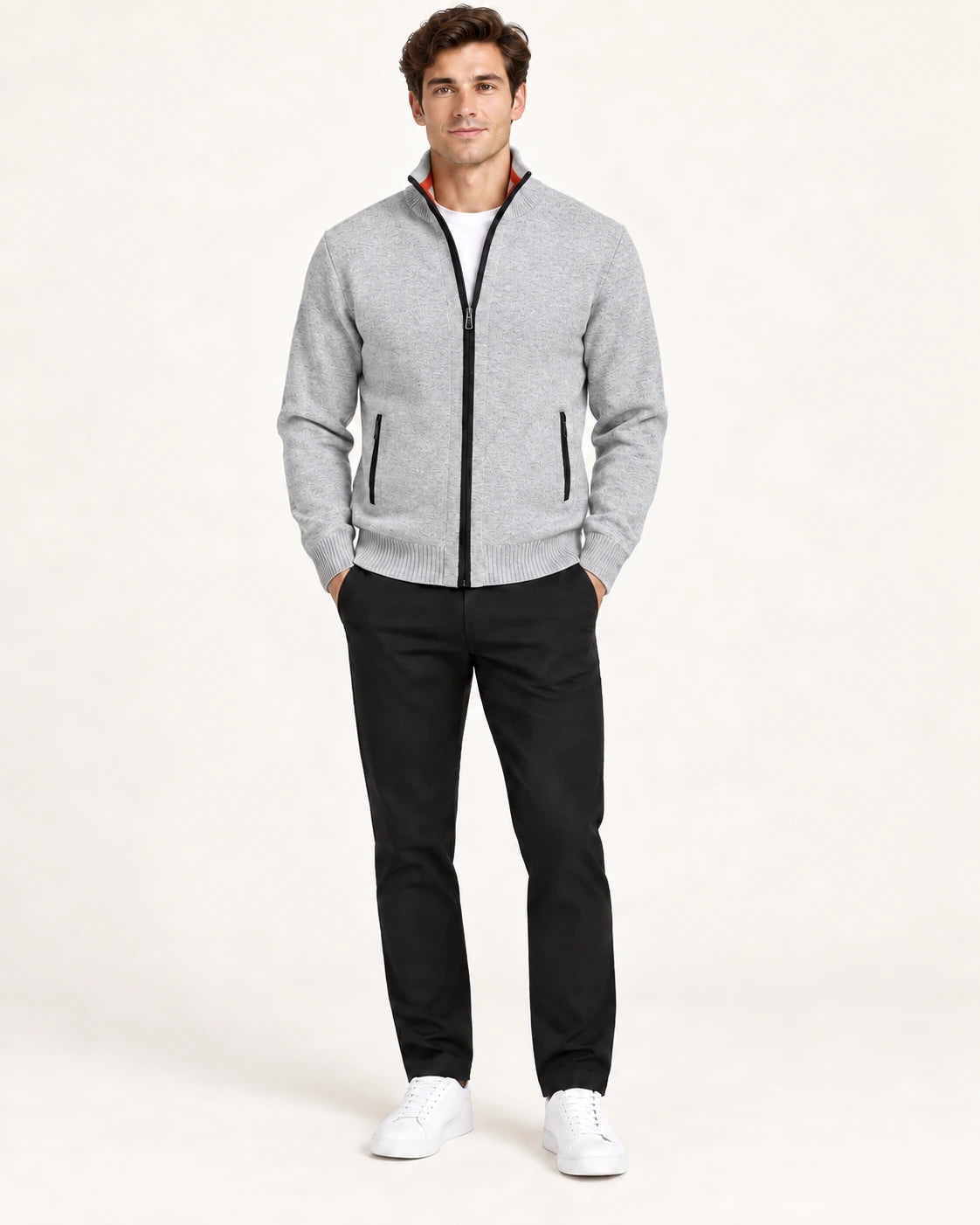 Gilet gris en maille fine avec col montant, fermeture centrale et deux poches zippées, porté de face dans le studio IVAREE.