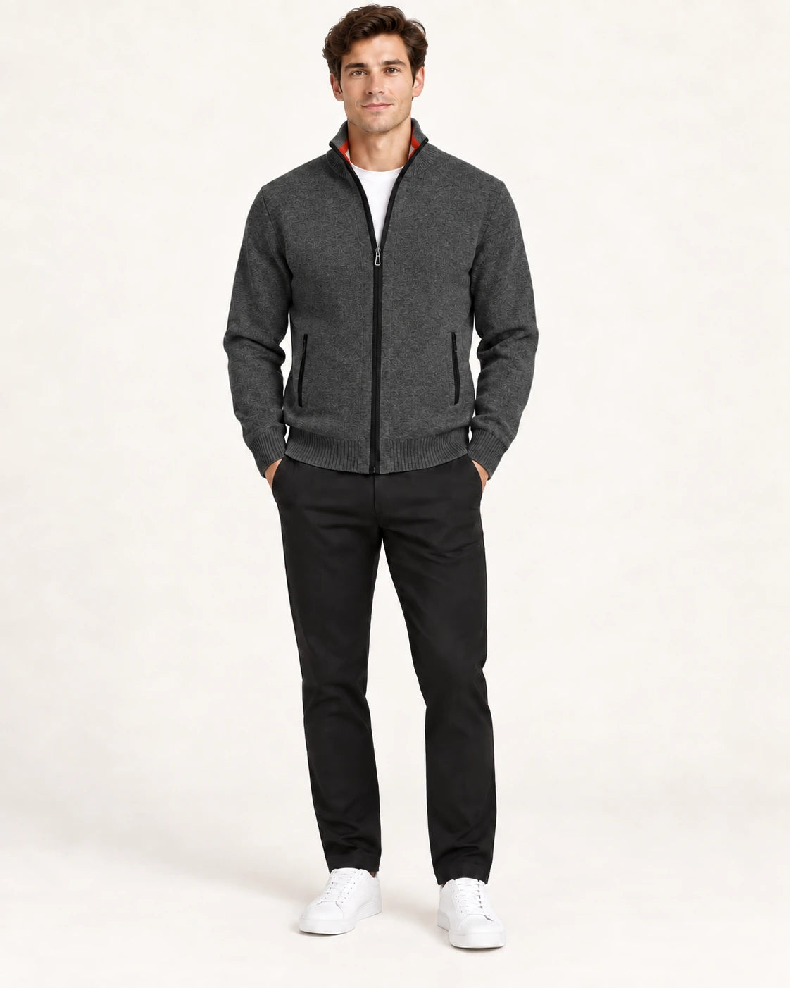 Gilet gris foncé en maille fine avec col montant, fermeture centrale et deux poches zippées, porté de face dans le studio IVAREE.