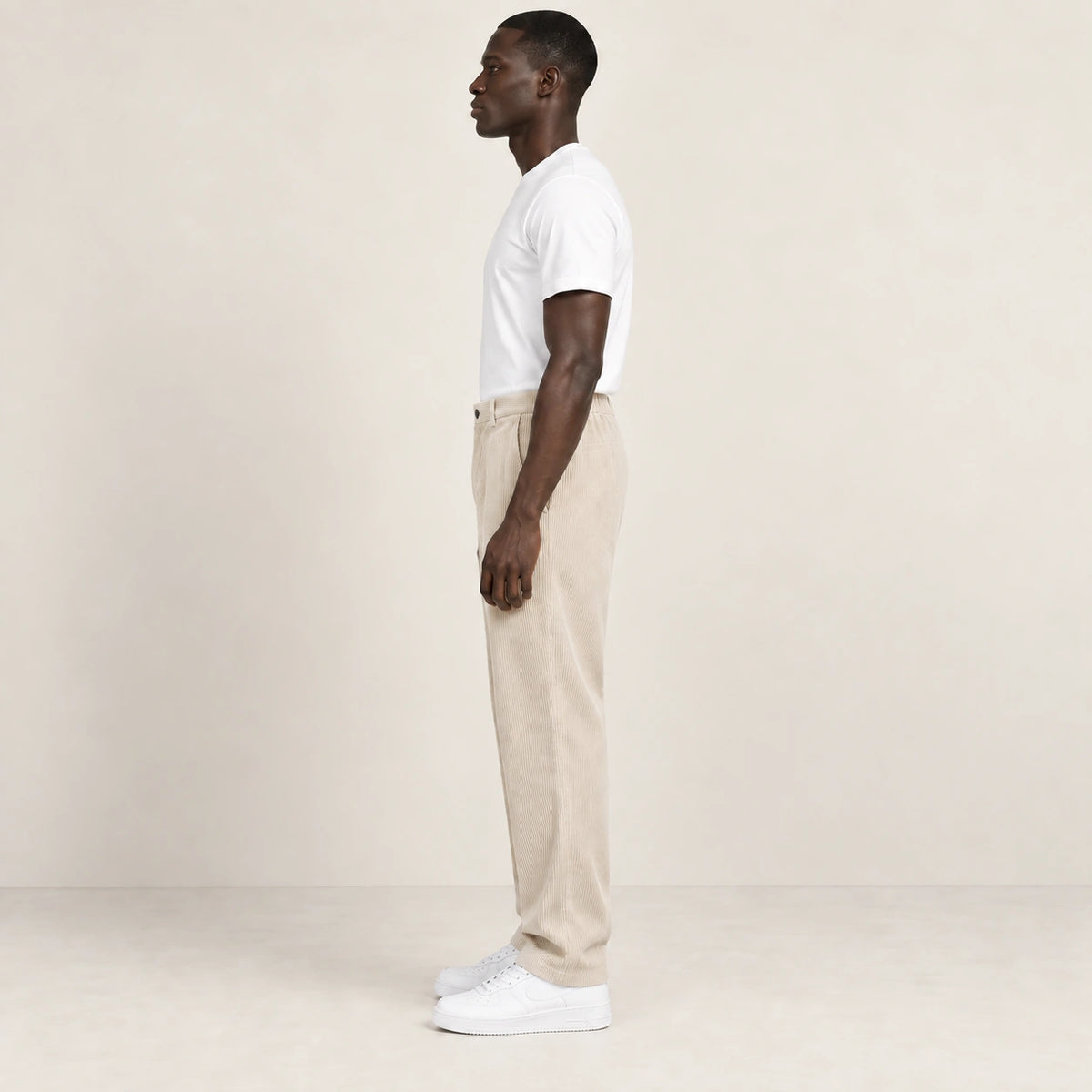 Pantalon beige en velours côtelé à fine rayure, profil dans le studio IVAREE