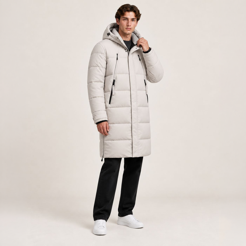 Parka longue beige matelassée à capuche, portée de trois-quarts avec une main au col dans le studio IVAREE, format carré 1:1.