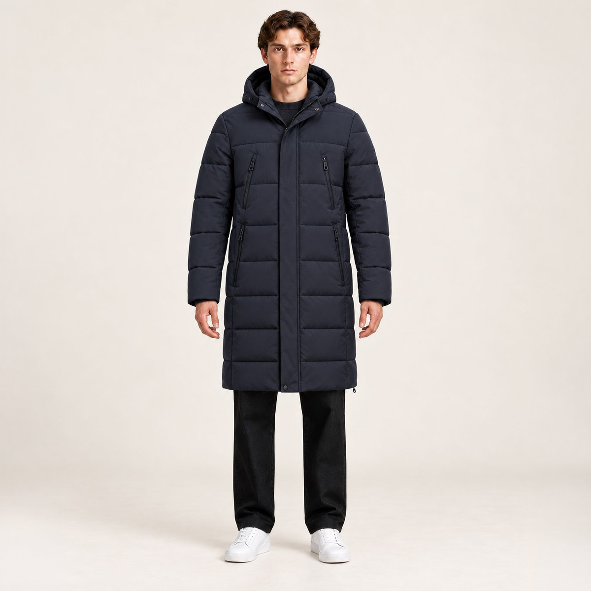 Parka longue bleu foncé matelassée à capuche et quatre poches zippées, vue de face dans le studio IVAREE, format carré 1:1.