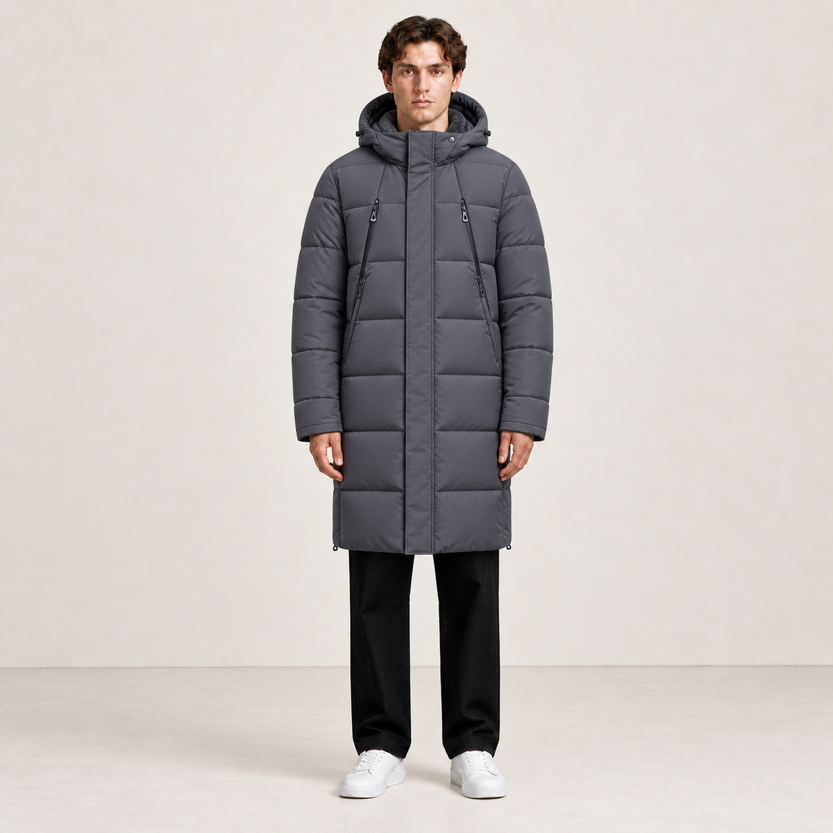 Parka longue grise matelassée à capuche et quatre poches zippées, vue de face dans le studio IVAREE, format carré 1:1.