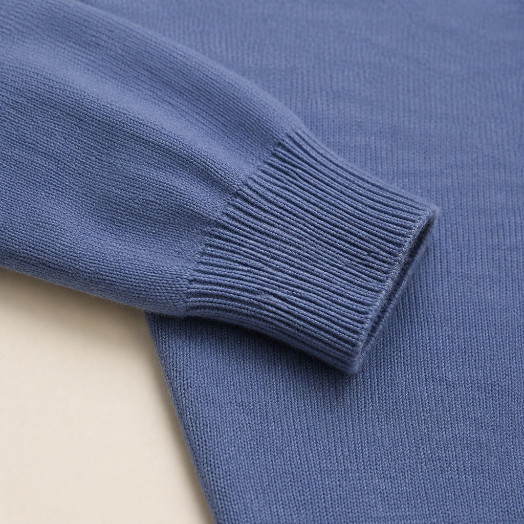 Détail du poignet côtelé et de la maille unie du pull col polo bleu.