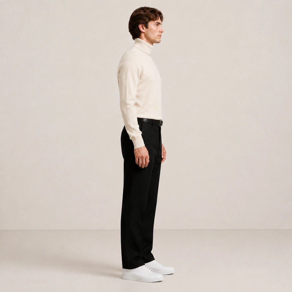 Pull col roulé beige clair en maille lisse, porté de profil en pied dans le studio IVAREE.