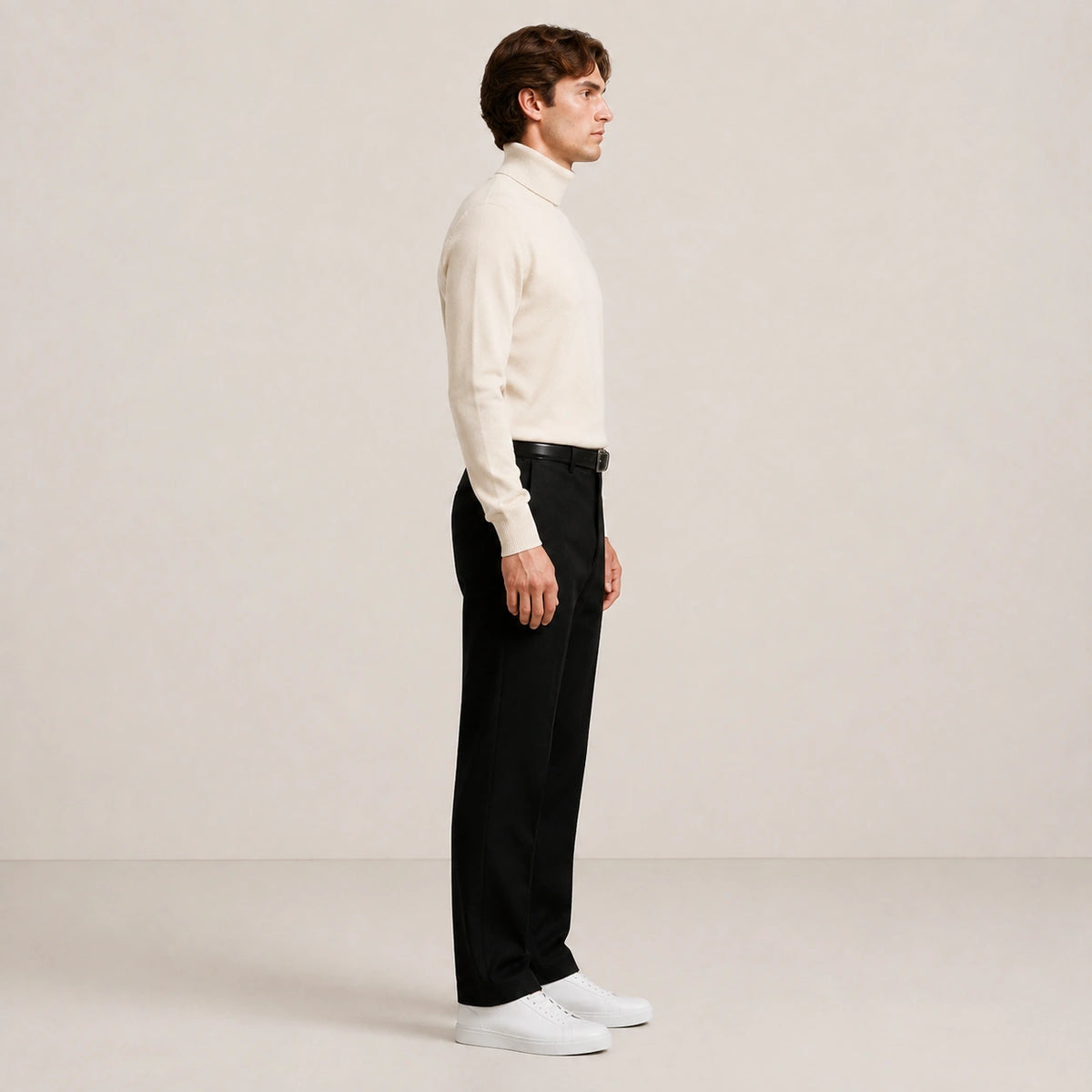 Pull col roulé beige clair en maille lisse, porté de profil en pied dans le studio IVAREE.