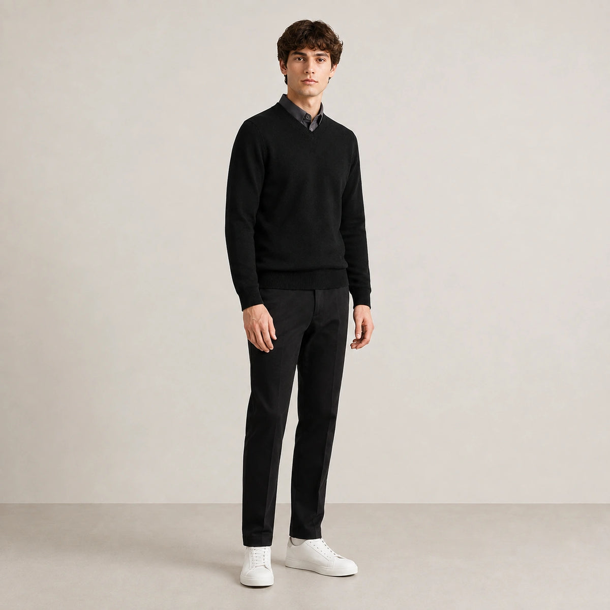 Pull col V noir en maille fine, porté de trois quarts dans le studio IVAREE.