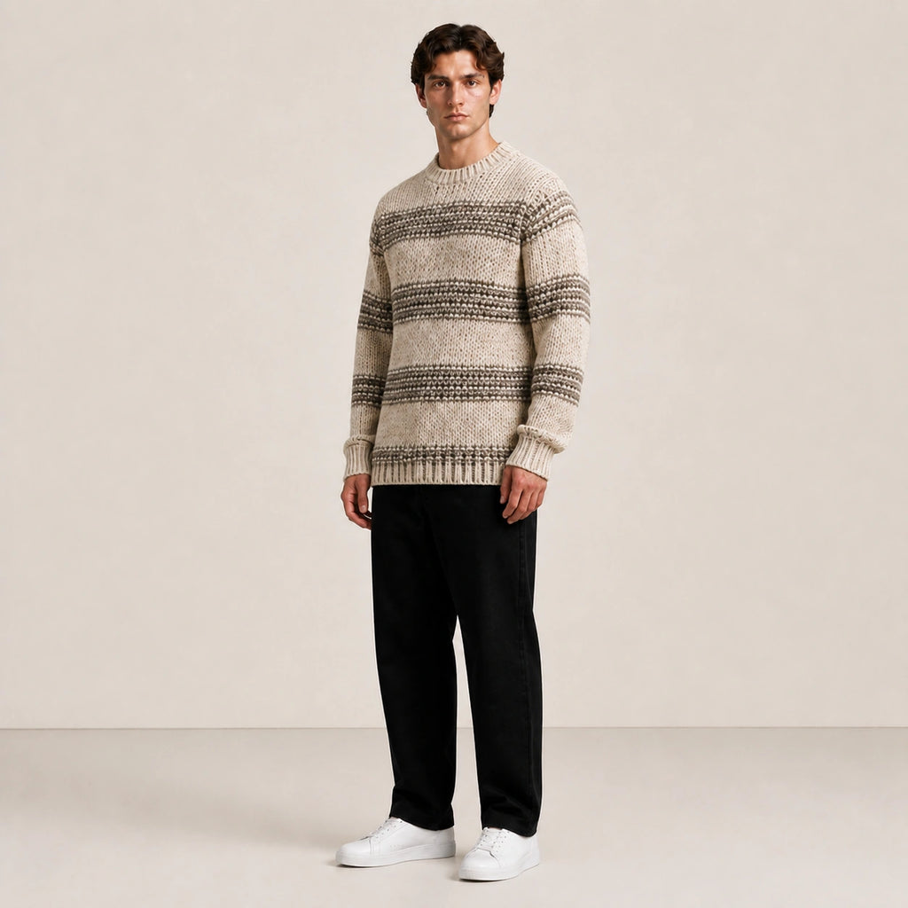 Pull homme en grosse maille beige à rayures, porté de trois-quarts en studio IVAREE.