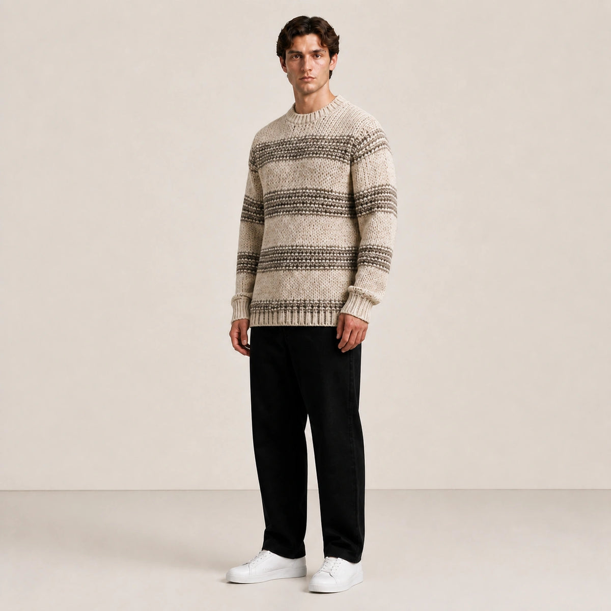 Pull homme en grosse maille beige à rayures, porté de trois-quarts en studio IVAREE.