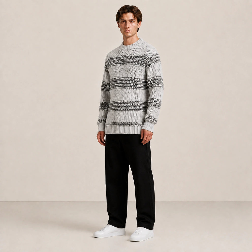 Pull homme en grosse maille gris à rayures, porté de trois-quarts en studio IVAREE.