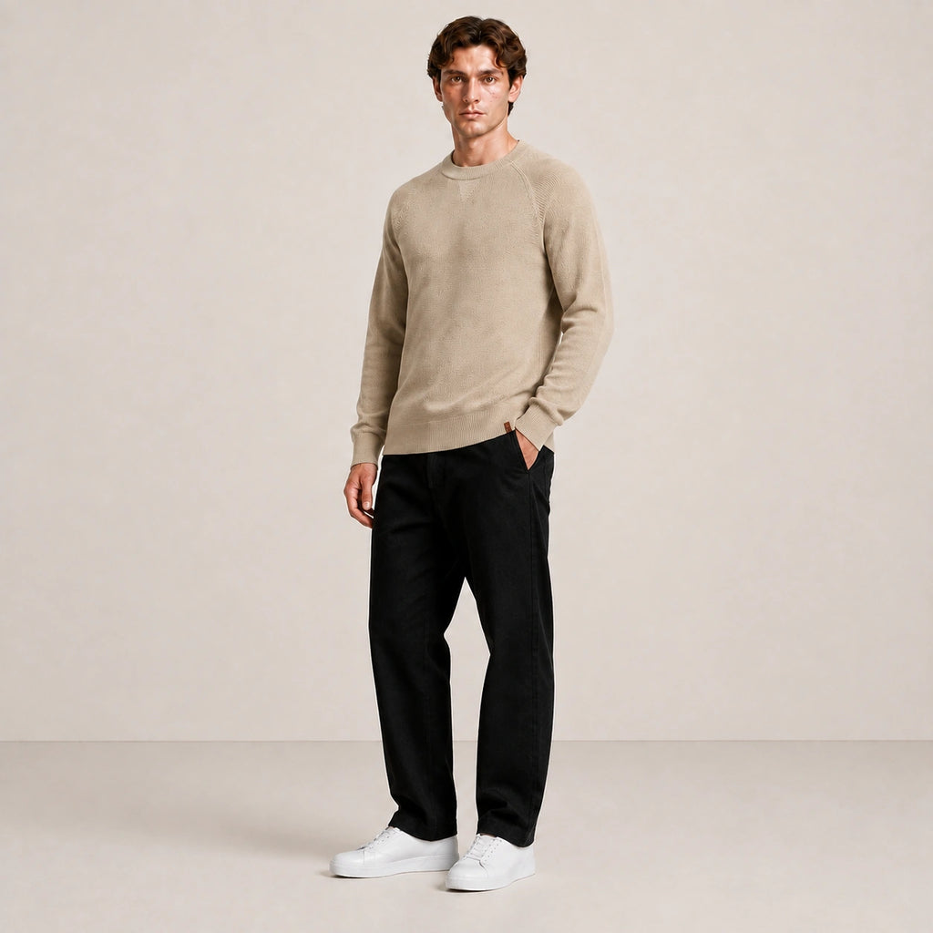 Pull homme beige, porté de trois-quarts en pied dans le studio IVAREE.