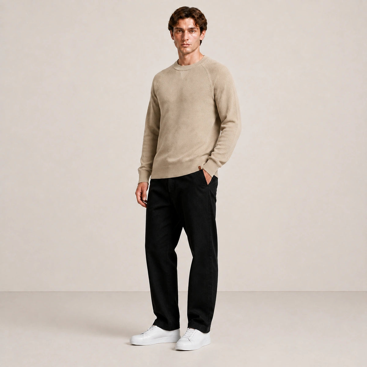 Pull homme beige, porté de trois-quarts en pied dans le studio IVAREE.