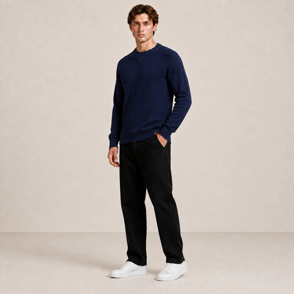 Pull homme bleu marine, porté de trois-quarts en pied dans le studio IVAREE.