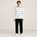 Pull rayé gris et blanc à col rond porté de face dans le studio IVAREE.