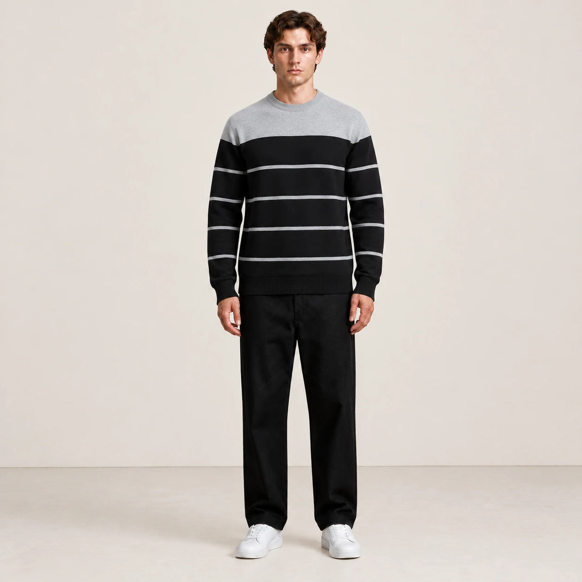 Pull rayé noir et gris à col rond porté de face dans le studio IVAREE.