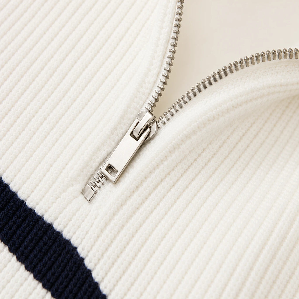 Détail de la fermeture zippée du pull rayé blanc et noir.